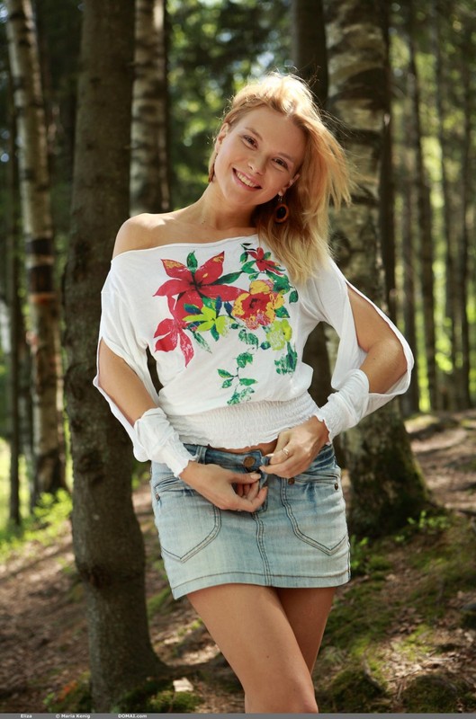 Красивая блондинка в белой футболке с принтом показывает стриптиз в лесу 6 фотография